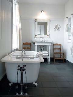 Porches Inn, North Adams, Massachusetts - Photo 12 of 21 - For a luxe evening soak, larger bathrooms (measuring 75-100 square feet) feature either Jacuzzi-style or claw-foot bathtubs with separate showers. The bathrooms also boast slate floors and distinctive touches like frosted glass and mirror frames salvaged from the building’s original window frames. Bathrobes and towels hang from metal wall pegs reminiscent of 19th-century Shaker design.