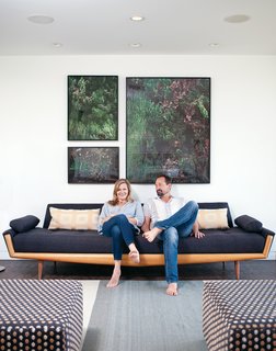 Gabbert and Avery relax on a vintage sofa in their living room beneath large-format photos of juniper bushes by Maegan Hill-Carroll.