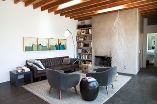 A family room off the kitchen is stocked with pieces from Room & Board, including the Wells sofa and gray Cable rug. The hanging sculpture is by Rebecca Niederlander and the quartet of paintings is by Babak Emanuel.
