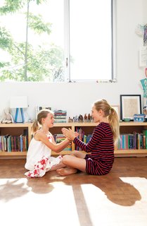 Daughters Ingrid and Jane play on the floor of their bedroom, laid with reclaimed end-grain parquet from Oregon Lumber.