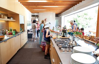 In the open-plan kitchen, bowls and platters by Heath Ceramics and bamboo trays and tongs from Design House Stockholm decorate the farm-to-table buffet on the steel-topped kitchen island.