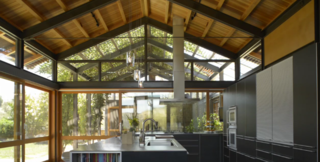 The house has a variety of indoor and outdoor spaces where the family can hang out, including a soaring kitchen and, through a big glass-walled door, an outdoor dining pavilion shaded by a vine-covered arbor.