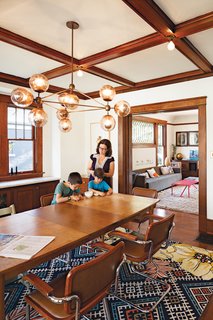 In the dining room, the vintage table and chairs are set off by a Modo Chandelier from Roll & Hill and a vibrantly patterned Anthropologie rug.