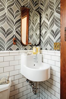 Playful wallpaper from Graham & Brown livens up the house’s otherwise staid powder room, which also contains a pint-size Ikea sink.