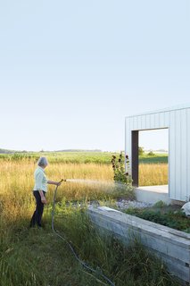 A Sustainably Built Home in Rural Ontario - Photo 3 of 16 - Maggie Treanor waters plants around her rural home.