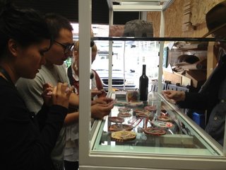 Open Studios at City Modern - Photo 12 of 26 - Chen Chen and Kai Williams met at Pratt studying industrial design, but it wasn't until 2011 they decided to form a design studio. Their work focuses on playful but natural designs. Here, Chen shows studio tour visitors a selection of their "lunch meat" coasters. A variety of materials melded together into a round form and slices are cut to become coasters.