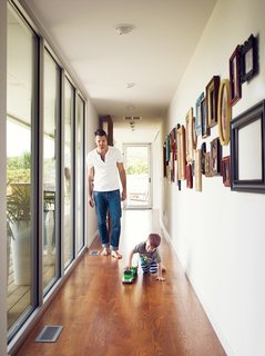 A Modern Farmhouse Recalls Old-Time Americana - Photo 2 of 10 - The hallway leading to the master bedroom is lined with an assortment of framed photos of family and friends and floor-to-ceiling windows overlooking the verdant James River Valley.