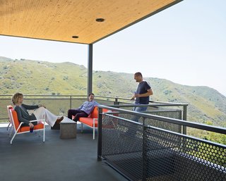Wright and Keffer (standing) hang out on their deck with Bolander, who lives just across the road. The chairs, designed by Bolander, are upholstered in Sunbrella fabric.