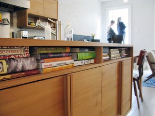 City Modern Home Tours: Brooklyn - Photo 51 of 51 - Cubby holes under the kitchen counter house cookbooks. The cabinets are made from salvaged wood. "The kitchen is where they like to be at home," Bischoff says. "That's why it's in the middle of the floor plan."