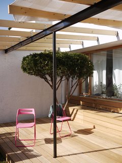 Being on the ground floor has its benefits—namely a bit of outdoor space. The black I-beam supporting the canopy of exposed joists offers a nice contrast to the wood above and below. Pink chairs do the trick as well.