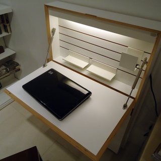One of the pieces installed in the model apartment is a fold-out desk cabinet called the Flatmate that's only four inches deep when closed. It features built-in interior lighting, cubbyholes along the sides for storage, and a power strip.
