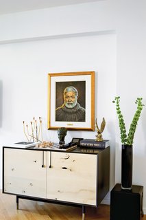 A Renovated Flat in Moshe Safdie's Habitat '67 - Photo 6 of 8 - In the living room, a Lake credenza by BDDW is topped with a Bauhaus chess set and a portrait of Ernest Hemingway by the artist Yuriy Rudnev.