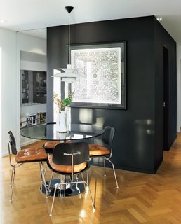 A Renovated Flat in Moshe Safdie's Habitat '67 - Photo 8 of 8 - In the dining area, a vintage table is surrounded by Eames DCM chairs topped with leather cushions custom-made by Peart. A PH5 pendant lamp by Poul Henningsen for Louis Poulsen hangs overhead.