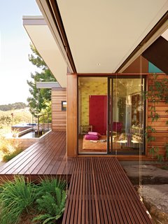 A Modern Prefab Addition to a Mid-Century California Classic - Photo 7 of 9 - A slatted walkway leads into the new library, which the Gimons have outfitted with a Topissimo rug by Nani Marquina, Grove Garden wallpaper from Osborne & Little’s Tara collection, and a pink Chroma Sassy sliding wall panel by 3form.