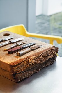 The kitchen, which the architect tucked into the back of the house, contains wooden cutting boards by Studio Simple and knives by Studio Simple and Antoine Van Loocke.