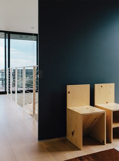 A sliding door separates the upstairs hall from the master bedroom, furnished with a pair of Donald Judd chairs.