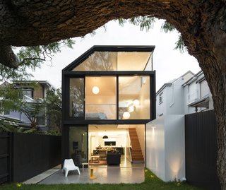 15 Modern Additions to Traditional Homes - Photo 7 of 15 - The addition’s two stories of cedar-framed sliding doors and window provide generous views of the house’s prized jacaranda tree. The addition’s polished concrete floor and white cladding extend into the garden, drawing occupants to the serene rear porch. There, they can relax on stools designed by Alvar Aalto and Charles Wilson while admiring the luscious greenery.