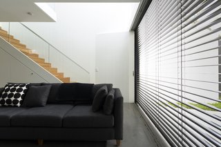 When the sun is at its brightest, the east-facing glass wall is shielded by retractable Horiso venetian blinds that have been powdercoated to match the extension’s charcoal cladding.