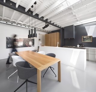 The kitchen area was built around the concept of different surfaces working together: stainless steel countertops for work, white Corian for preparation, and solid white oak for storage. A landscape painting by Chabauty's grandfather hangs above the sink, adding a note of serenity to the room. The kitchen contains a Viking range and oven, a Bosch 800 Plus Series dishwasher, a KWC Eve faucet, a Liebherr HRB 1100 refrigerator. Artek A110 Pendants hang above the dining table, a custom oak piece surrounded by chairs from HAY.