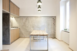 "It was supposed to be as naked as possible," says Alexandru Popescu, one of the members of R3Architetti who helped design and build the 3 Vaults apartment. "The furniture is absolutely included in the architecture; it’s more like an indoor landscape instead of a typical open plan." The kitchen exemplifies their approach, with textured concrete walls contrasting with wood panels and salvaged industrial lighting. The table, custom built by R3Architetti, is made in part from pipes procured from one of their fathers, a plumber.