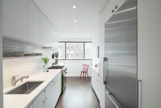 These 30 White Kitchens Are Anything But Ordinary - Photo 23 of 30 - The homeowners, who are avid cooks, worked with a design duo and contractor for the home's renovation. To make the kitchen seem larger than it is, the team decided to place the largest cabinets and appliances near the entryway, making less clutter toward the window.