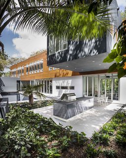 This Modern Miami House Feels Like It's in the Middle of the Jungle - Photo 5 of 12 - An elegant pool and outdoor kitchen extend from the living areas.