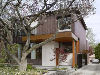 Smart Tech Makes this Modern Home Ultra Energy Efficient - Photo 2 of 11 - The house responds to its site. "The design was directly influenced by two mature, century-old magnolia trees in the front and a Japanese maple in the rear," Tedesco says. "The location of widows and main program spaces, such as the living room and master bedroom, were strategically placed to take full advantage of views of these trees. Because the trees are fully visible from the interior, seasons and the trees' yearly blooming cycles play a significant role in daily life—they're not just landscape elements. The window sizes and their locations were coordinated with the existing trees to take advantage of passive solar shading in the summer and solar gain in the winter months when the trees do not have foliage."