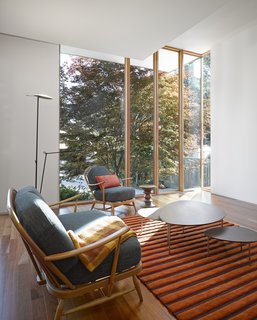 Smart Tech Makes this Modern Home Ultra Energy Efficient - Photo 3 of 11 - The flooring throughout the interior is maple. A vintage Ercol sofa and arm chair, Eclipse coffee table by Stua, Wide Wale rug by Bev Hisey Textile Design, and Moon floor lamp by Estiluz Spain furnish the living room. "Extensive planning went into 'aging in place' forecasting a host of different scenarios about what that meant physically and psychologically," Tedesco says. "We did 'day in the life' modeling to understand all the various barrier free requirements that might arise. This heavily influenced the design of the house especially in the flow of circulation and the size of specific elements including the corridors, door widths, washrooms (showers, sinks and toilets design and location) and bedrooms. Finally the entry sequence from the driveway and the walkway to the front and side doors were designed to be future proofed to allow aging in place."