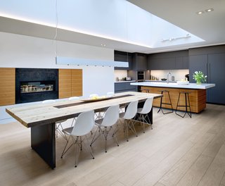 From a Flower Bulb Factory to an Entertainment Hub - Photo 4 of 9 - The kitchen also displays a reliance on natural materials and soft colors. For the wine storage area, Roundabout Studio used reclaimed wood from the original building. The new dining room table also utilizes repurposed studs salvaged from the building’s demolition. The kitchen stools are from Avenue Road, the dining room table is custom, and the pendant light is from Dark Tools.