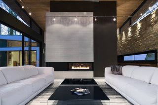 The clients asked for interior products in thirteen shades of white, including the twin Malibu sofas by American Leather. Interior designer Burns Century added deeply hued textures such as the charcoal suede on the fireplace column to keep the room feeling natural, not icy. The black Pool coffee tables are from Design Within Reach.