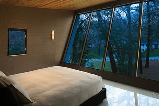 Lustrous textures characterize the cantilevered master bedroom. The gleaming four-square-foot white porcelain tiles are softened by crushed-shell wallpaper and a cypress ceiling.