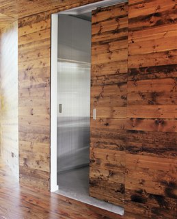 The wooden doors in the living room practically vanish when closed. Sliding them open reveals modern bedroom suites in a lighter, brighter palette.