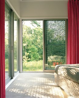 Perforated metal on the exterior of this home filters light coming in, providing shade and a desired aesthetic effect on the interior and exterior.