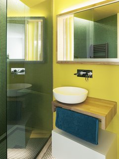 "The bathrooms were conceived as special spaces," Vázquez says. "We decided to give them some color that would contrast with the main spaces." A vessel sink by Cubik rests on a custom oak base; the mosaic tile is from Mosaico.