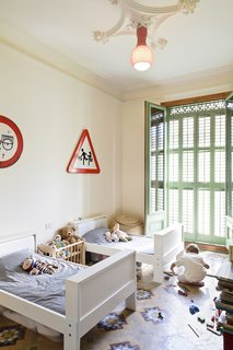 The architects’ two young children occupy this bright bedroom, furnished with Ikea beds. Another custom lamp illuminates the space.
