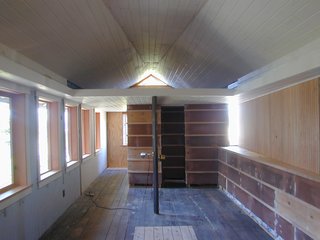 Tiny 1920s Garage Transformed Into a Charming Studio - Photo 4 of 8 - BEFORE<br><br>After being used as an auto repair shop, the garage had been subdivided to include a dark storage area with an unsettingly low ceiling. Schaer opened up the space, replacing the collar ties in the rafters with a sloping triangular plane that Schaer says "draws the eye from one end of the space to the other, increasing its perceived size." It’s also utilitarian, providing natural ventilation by funneling hot air up through a triangular vent window.