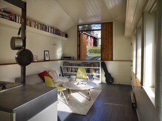 Tiny 1920s Garage Transformed Into a Charming Studio - Photo 5 of 8 - The compact rental features plenty of wooden ledges, nooks, and shelves for keeping belongings organized. In the living room, a low white wall is capped with fir wood salvaged from the garage’s former posts. On the east wall, a half-door made of reclaimed cedar looks out on a garden. "It looks and lives a lot bigger than it is," Schaer says.