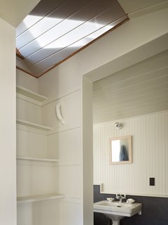 Tiny 1920s Garage Transformed Into a Charming Studio - Photo 7 of 8 - At left, steps lead up to a sleeping loft. In the bathroom, Schaer installed a salvaged clawfoot bath and toilet and marmoleum click floorboards. Wainscoting on the walls adds a delicate touch.