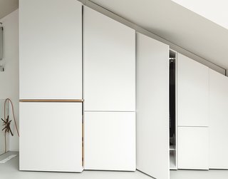 Custom storage lines the angled wall of a bedroom loft.