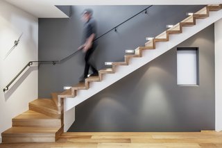 10 Warm Wood Floors - Photo 9 of 10 - Behind the living room, a minimalist staircase leads to the upper level’s bedroom and family room. White oak flooring unites the staircase and the rest of the living spaces.