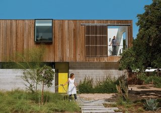 Austin couple Anne Suttles and Sam Shah built a house to last their lifetime—and longer. Mixing new efficient systems with old upcycled materials in their home, they keep it weird while keeping it green.<br><br>Here, Anne waters the bamboo muhly, palo verde, strawberry tree, and magic carpet thyme thriving in their yard.<br><br>Photo by: Brent Humphreys