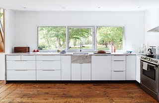 The new custom kitchen is situated in the original structure. The window is a new commercial unit with an operable frameless center pane and was set so that the countertop could tuck right underneath it to create a 1/4-inch shadow line.