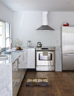 The updated kitchen is outfitted with stainless steel appliances, including a Bosch range, a Fisher & Paykel refrigerator, and a Frigidaire range hood. The faucet is Hudson Reed.