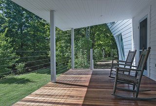 The client requested a porch, so Givone built one with columns made of anodized aluminum, the same material used in the siding of the addition, and stainless steel cables. "Even though it's a traditional, covered porch, it has very modern materials," he says.