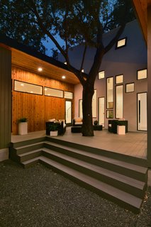 15 Brilliant Designs That Work Around Nature - Photo 12 of 15 - The central oak tree sprouts out of the rear deck. The atrium’s array of windows draw the eye in the tree’s direction. The wood cladding of the single-story wings provide a pleasant contrast with the central volume’s stucco finish.