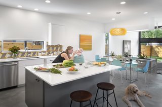 In the airy kitchen, meals are prepared on a Silestone White Storm countertop. The backsplash’s tiles match those on the staircase’s risers. In the adjoining dining area, a Caboche suspension light by Foscarini hangs over a CB2 dining table and Real Good Chairs by Blu Dot.