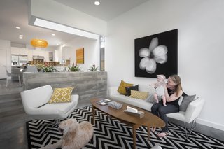 The living room sits a few steps down from the kitchen-dining area, and is demarcated by a board-formed concrete planter. Occupants can gather in the Blu Dot sofa and chair. Amid the concrete and fabric, an Ikea coffee table provides a warm wooden touch.