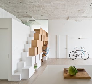 10 Smart and Surprising Under-Stair Design Solutions - Photo 7 of 10 - In the family room of this former industrial loft in Brooklyn that was renovated by SABO project, a new staircase leads to a mezzanine level. The alternating tread steps double as cabinets that are free of knobs and visible hardware, creating a graphic statement piece in the room. The cabinets give way to a workspace that's complete with open and closed shelving so that the space can remain uncluttered.