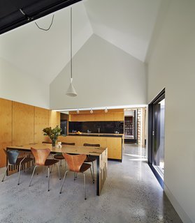 The dining room serves as the hub for all activity. Original Series 7 chairs by Arne Jacobsen complement a table Maynard designed and dubbed the "Zero Waste Table," since it utilizes every inch of a large wood sheet. To the right, a sliding door opens to the garden.