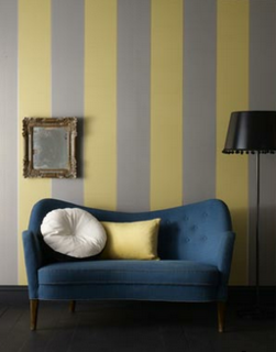 From designer staple Graham & Brown, the muted gray and mustard striped wallpaper pairs nicely with the warm tones in the mid-century furniture.